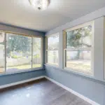 Enclosed sunroom with wide replacement windows and vinyl flooring