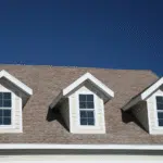 Three dormer windows set into an asphalt shingle roof