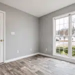 Bedroom corner with a replacement window and neutral walls