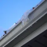 Close view of a gutter and fascia with water and ice at the edge
