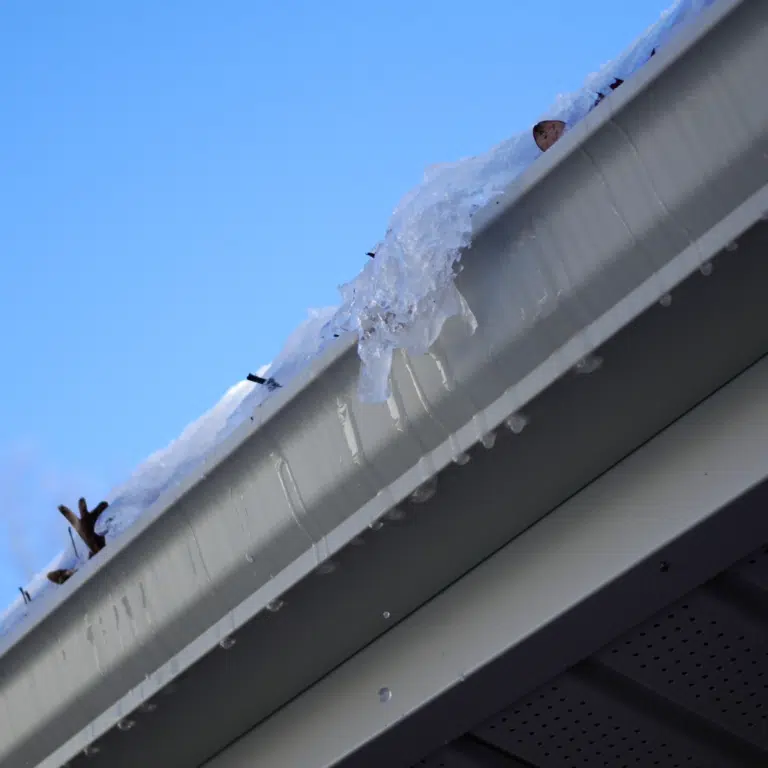 Close view of a gutter and fascia with water and ice at the edge