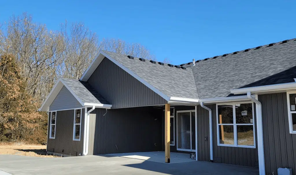 New construction home with dark siding and a completed roof