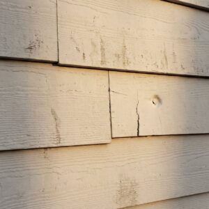 Cracked and punctured lap siding on an exterior wall