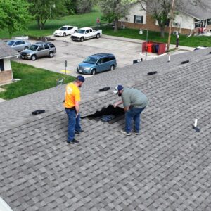 Two roofers working on a residential shingle roof repair