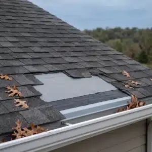 Home | Teague Roofing Plus 57 Wind-torn asphalt shingles at a roof edge exposing gray synthetic underlayment over a black ice and water shield strip above the drip edge